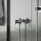 Brausearmatur von Ideal Standard in Chrom, an der Wand installiert, mit einem feststehenden und einem flexiblen Schlauch. Oberfläche ist glänzend und reflektiert das Licht.